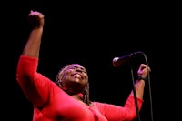 a woman in a red shirt singing into a microphone